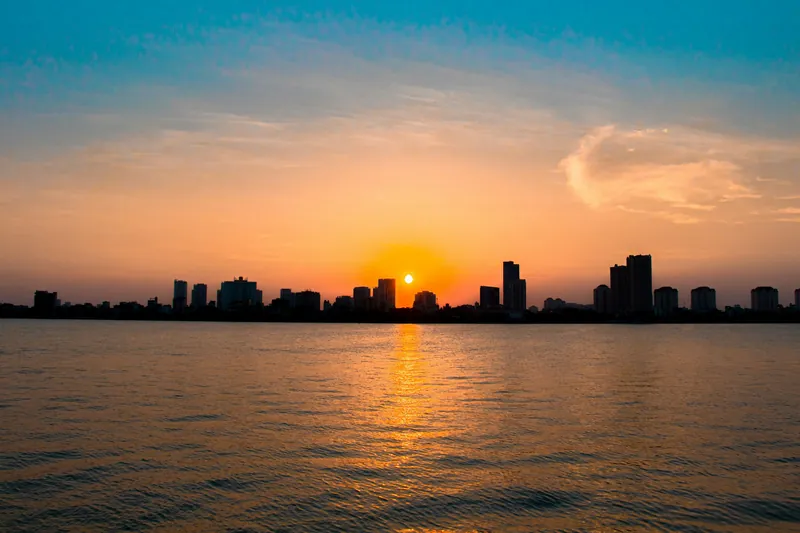 The sun setting over West Lake in Hanoi, with the skyline beyond